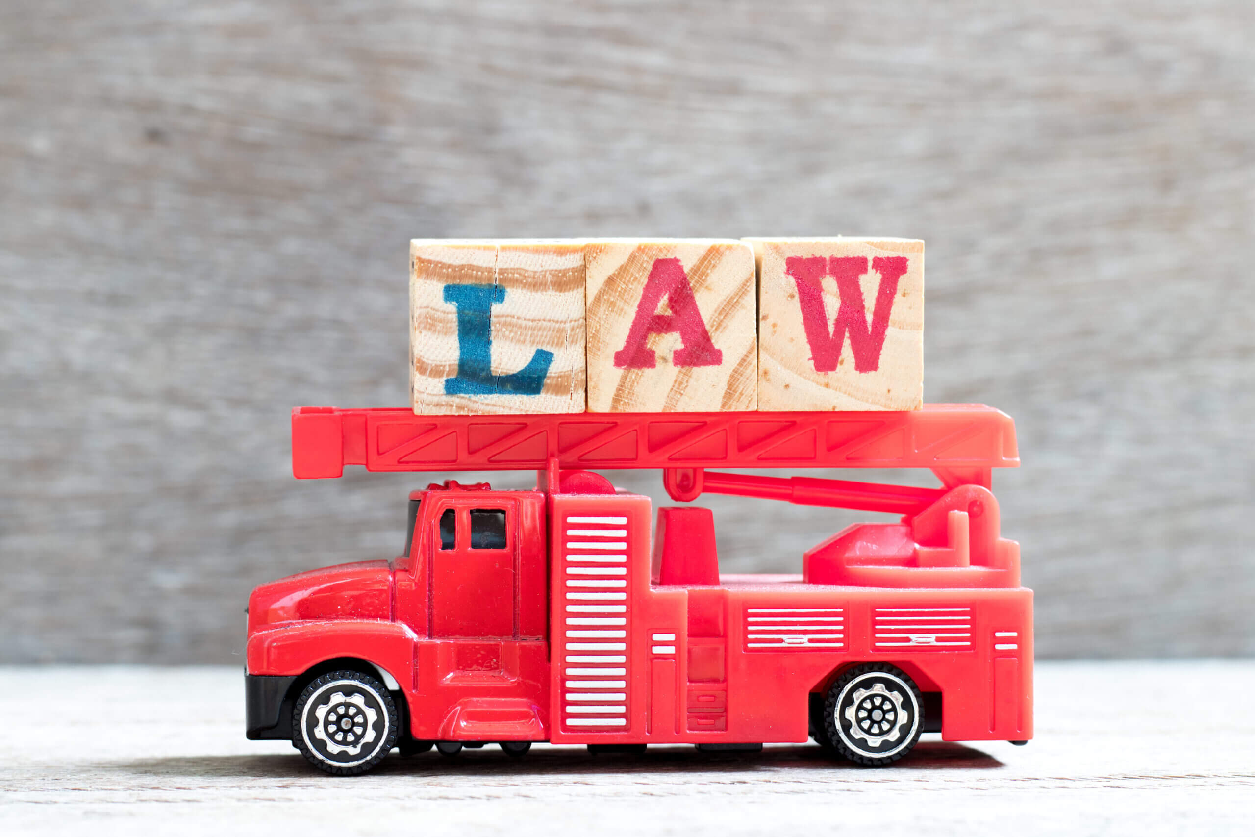 Toy fire ladder truck hold letter block in word law on wood background